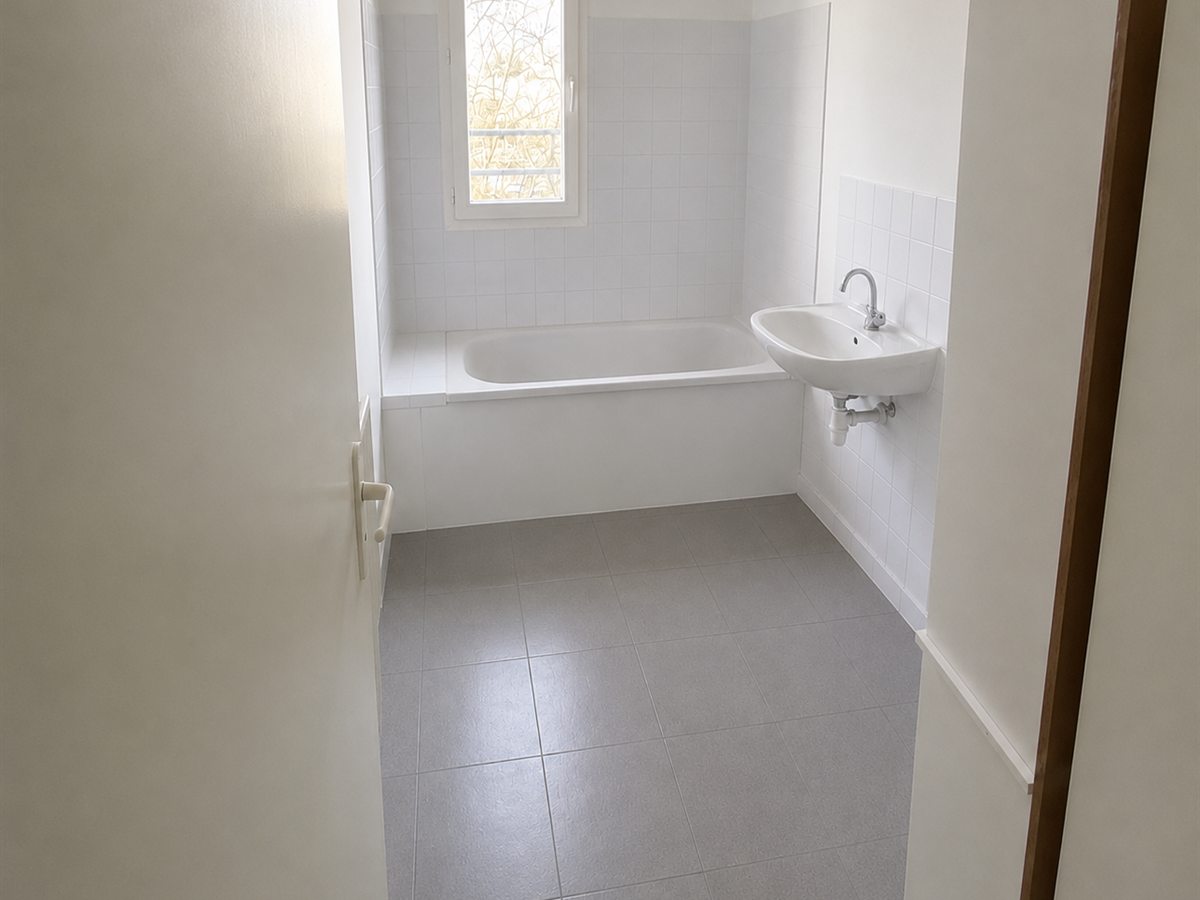 La même salle de bains après intervention : sol, murs, baignoire et lavabo remis à neuf et désinfectés.